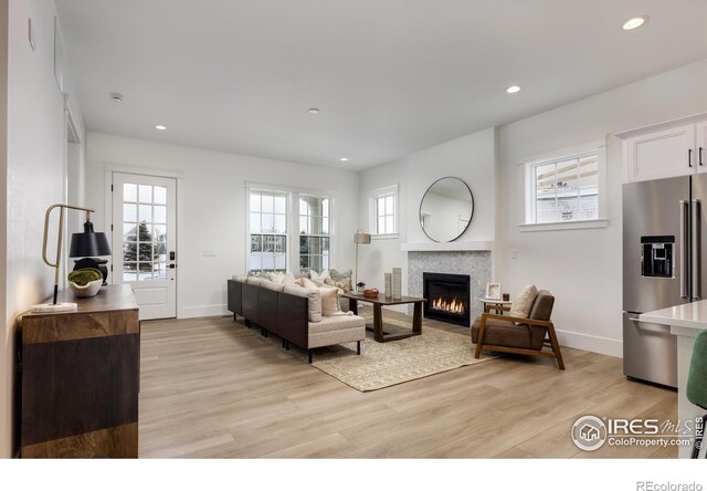 living room featuring a tiled fireplace and light hardwood / wood-style floors