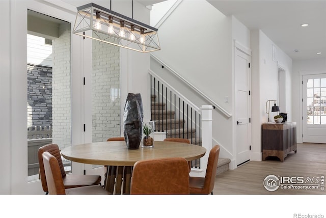 dining space with brick wall and light hardwood / wood-style floors