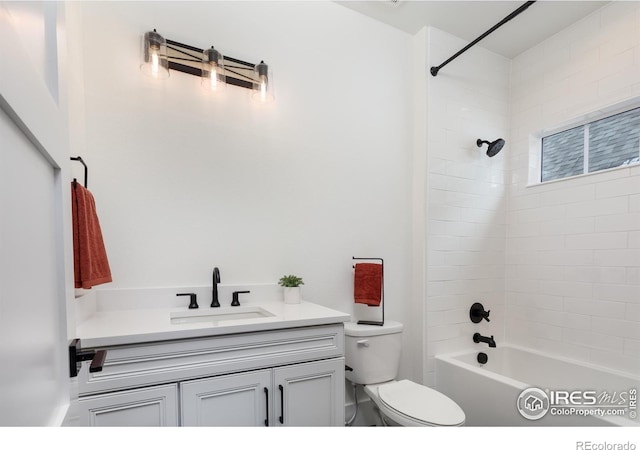 full bathroom featuring vanity, tiled shower / bath, and toilet