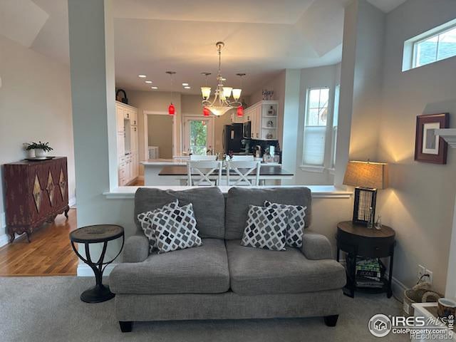 living area with an inviting chandelier, plenty of natural light, wood finished floors, and baseboards