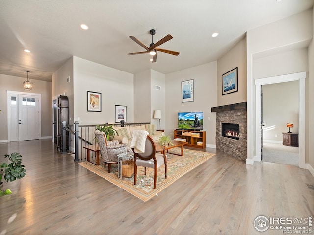 living room featuring baseboards, ceiling fan, wood finished floors, a fireplace, and recessed lighting