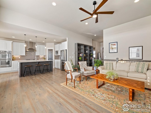 living room with ceiling fan, light wood finished floors, and recessed lighting