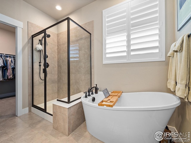 bathroom featuring a stall shower, a freestanding bath, and tile patterned floors