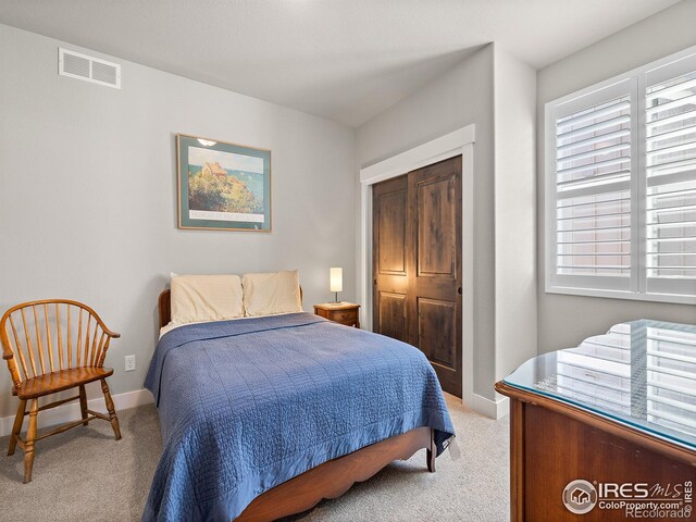 bedroom with baseboards, visible vents, a closet, and light colored carpet