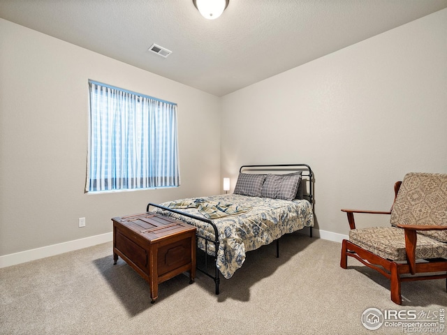 bedroom featuring carpet, visible vents, a textured ceiling, and baseboards