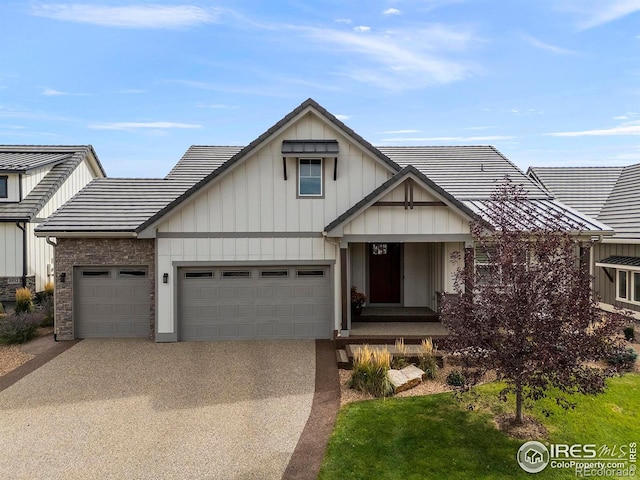 view of front of house with driveway, board and batten siding, an attached garage, and a tile roof