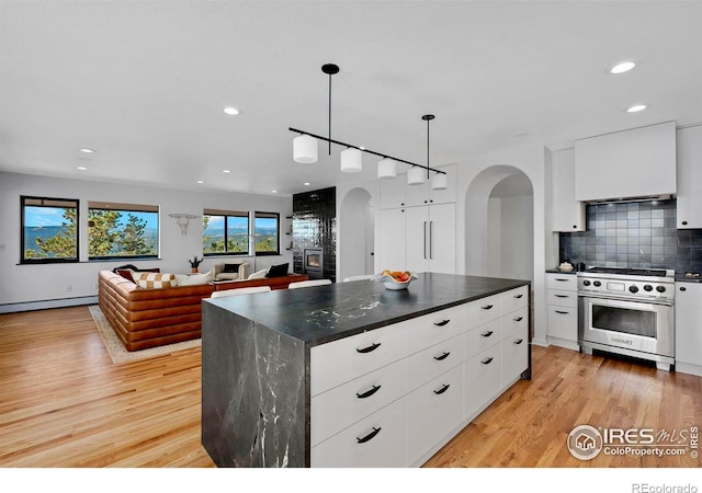 kitchen with white cabinetry, high end stainless steel range, light hardwood / wood-style floors, and decorative light fixtures