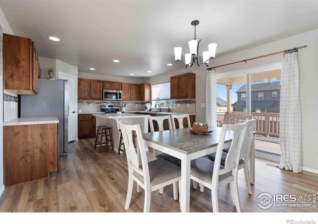 dining space featuring an inviting chandelier, sink, and wood-type flooring