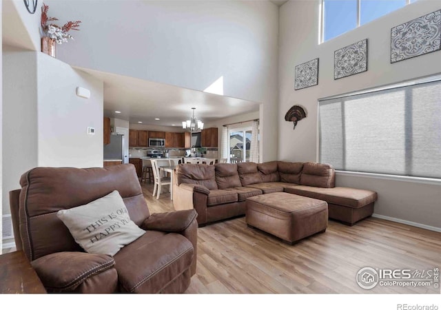 living room with light hardwood / wood-style floors, a chandelier, and a high ceiling