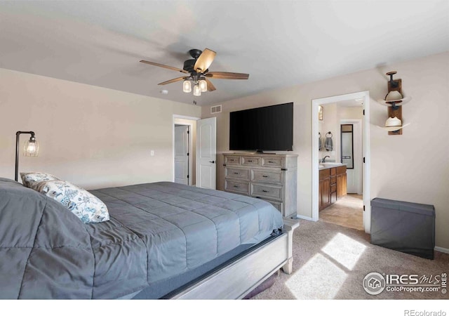 bedroom featuring ensuite bathroom, light carpet, and ceiling fan