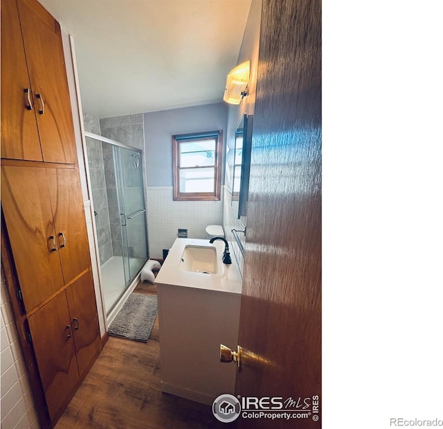 180 W 3rd St S, Cheyenne Wells, CO 80810 - bathroom with vanity, tile walls, a shower stall, wood finished floors, and a wainscoted wall