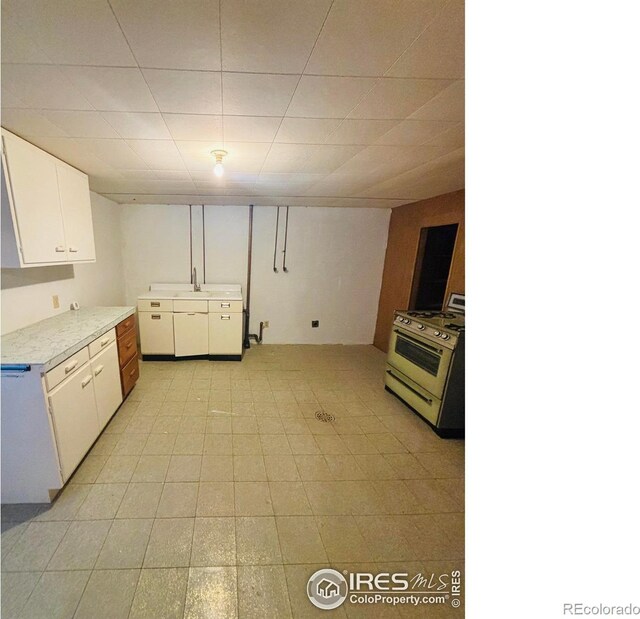 180 W 3rd St S, Cheyenne Wells, CO 80810 - kitchen with gas range, white cabinets, and light countertops