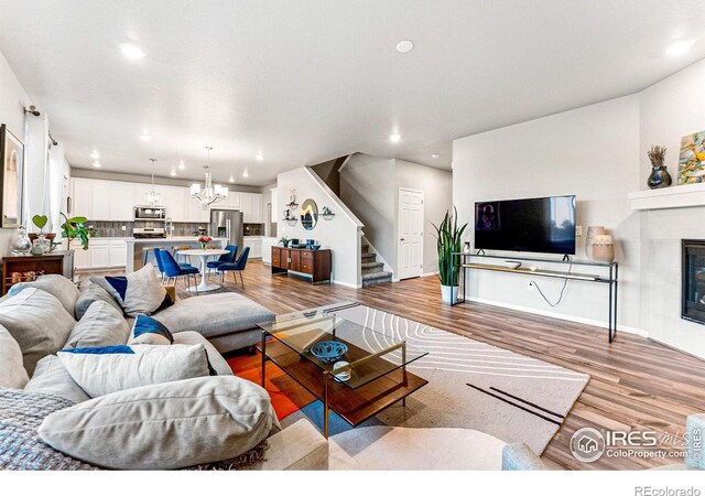 living room with a tiled fireplace, light hardwood / wood-style floors, and a notable chandelier