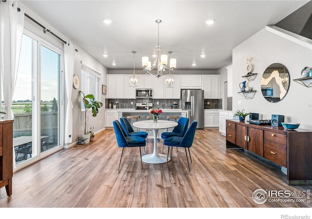 dining space with a notable chandelier and light hardwood / wood-style floors