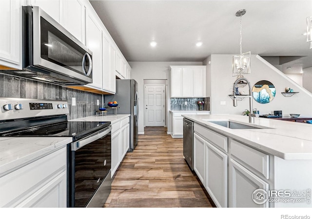 kitchen featuring stainless steel appliances, light stone countertops, hanging light fixtures, and white cabinets