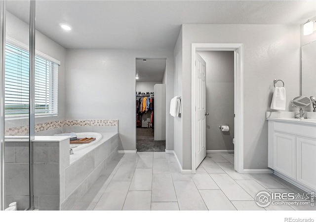 bathroom featuring vanity, tiled bath, and tile patterned flooring