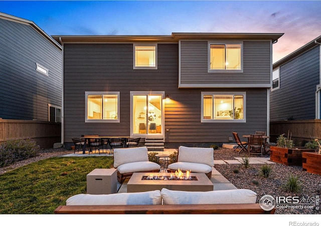 back house at dusk featuring a patio and an outdoor fire pit