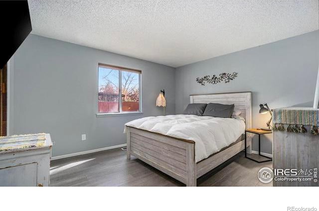 bedroom with dark hardwood / wood-style floors and a textured ceiling