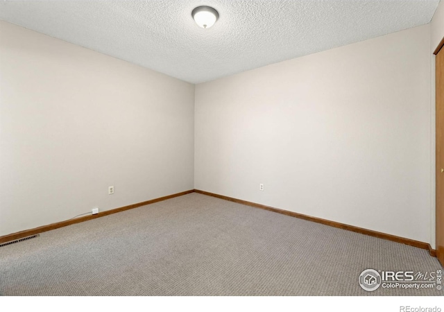 empty room featuring carpet and a textured ceiling