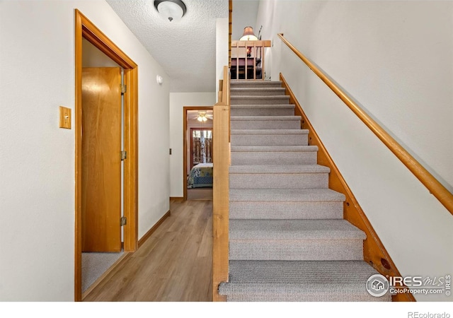 staircase with wood-type flooring and a textured ceiling