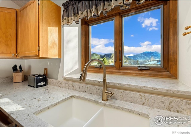 interior details featuring a mountain view, sink, and light stone countertops