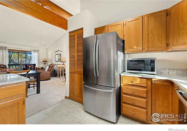 kitchen with lofted ceiling with beams, light tile patterned floors, and stainless steel appliances