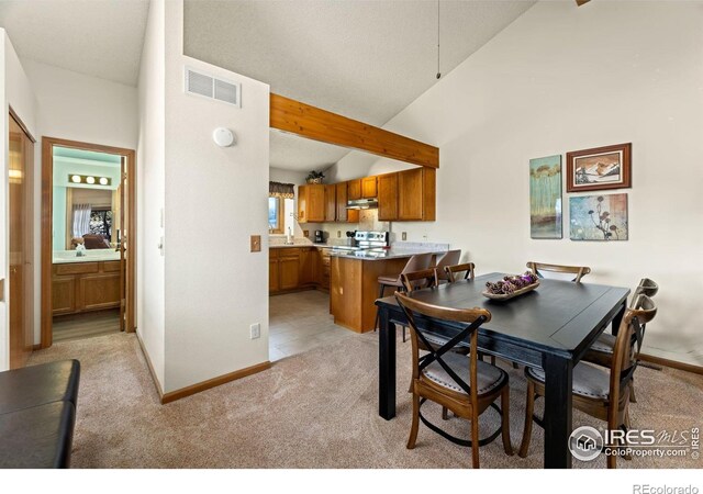 dining space with high vaulted ceiling, sink, and light carpet