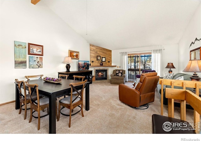 carpeted dining space with high vaulted ceiling and a large fireplace