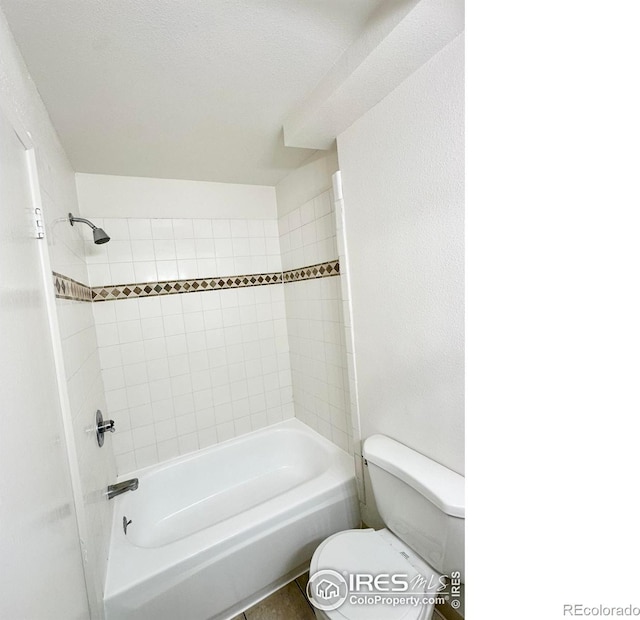 bathroom featuring toilet and tiled shower / bath