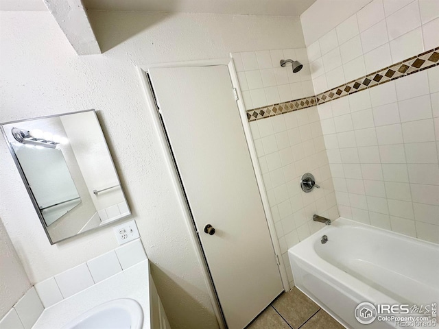 bathroom featuring tile patterned flooring, vanity, and tiled shower / bath