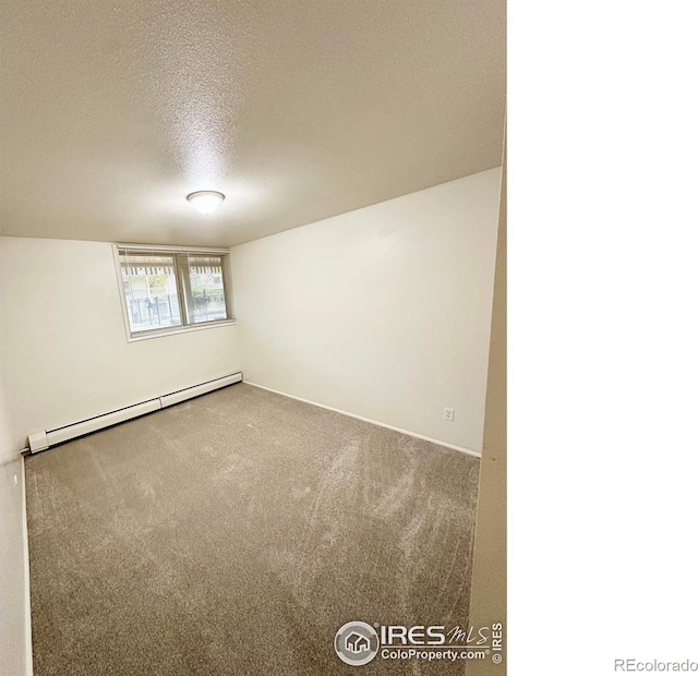 empty room featuring a baseboard heating unit, carpet flooring, and a textured ceiling