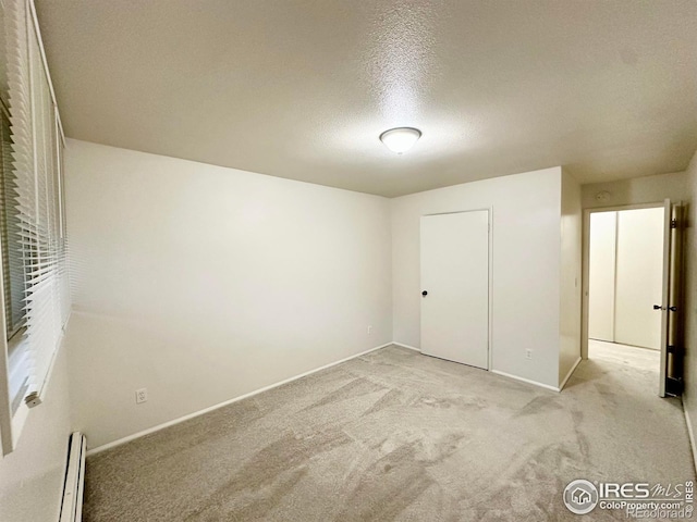 unfurnished bedroom featuring a baseboard radiator, light carpet, and a textured ceiling