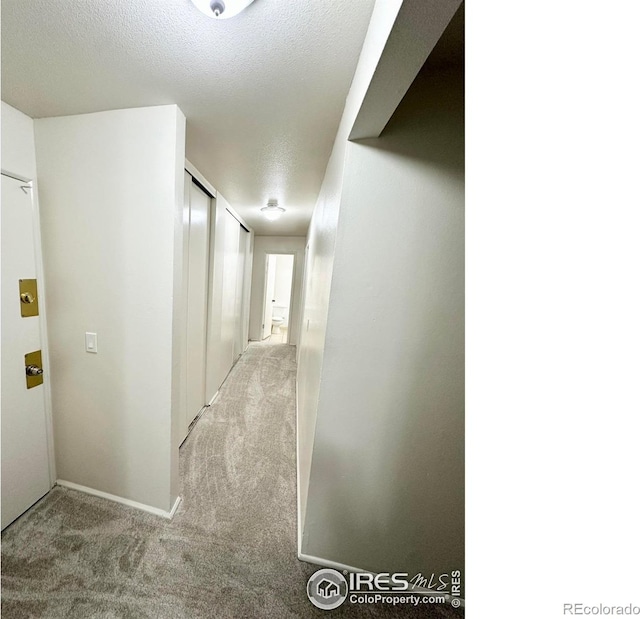 hall with light carpet and a textured ceiling