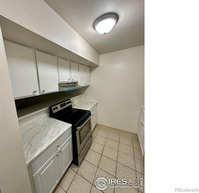 kitchen with white cabinets, light tile patterned floors, electric range, and a textured ceiling