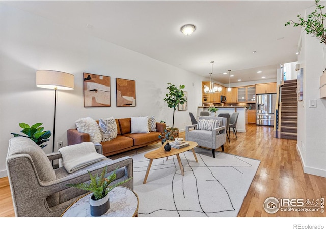 living room with light wood-type flooring and an inviting chandelier