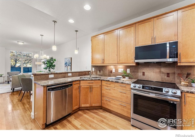 kitchen featuring stone counters, light hardwood / wood-style floors, hanging light fixtures, and appliances with stainless steel finishes