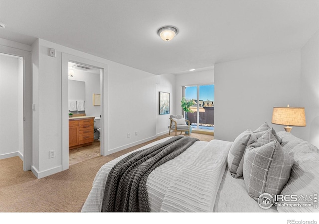 bedroom featuring light carpet and connected bathroom