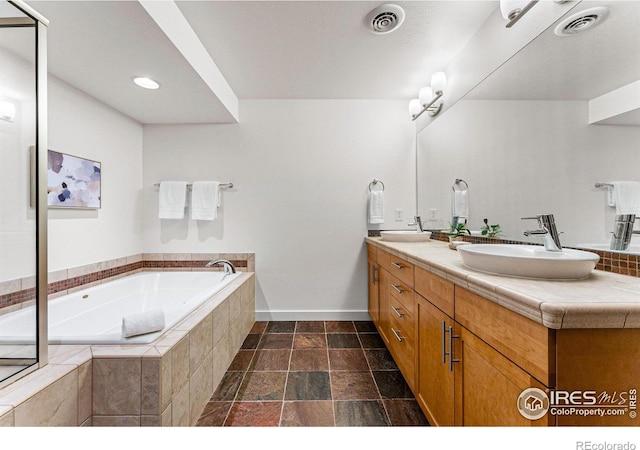 bathroom with vanity and tiled bath