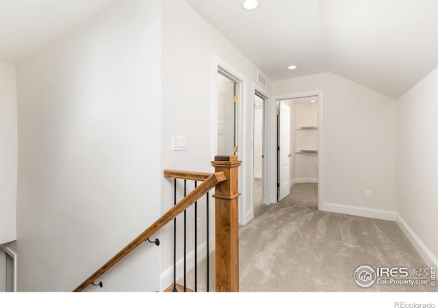 corridor with lofted ceiling and light carpet