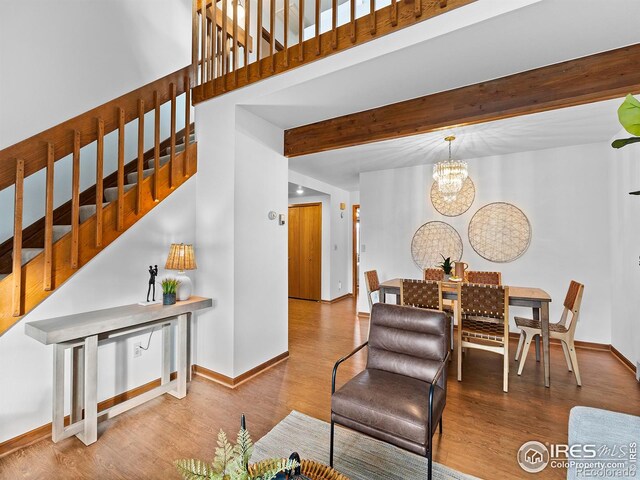 living room featuring beamed ceiling, wood-type flooring, and a notable chandelier