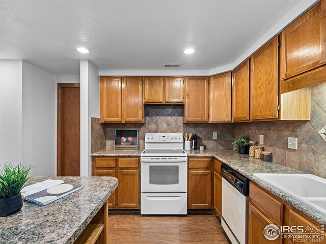 kitchen featuring white electric range, wood-type flooring, decorative backsplash, stainless steel dishwasher, and light stone countertops