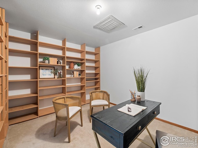 carpeted home office featuring a textured ceiling