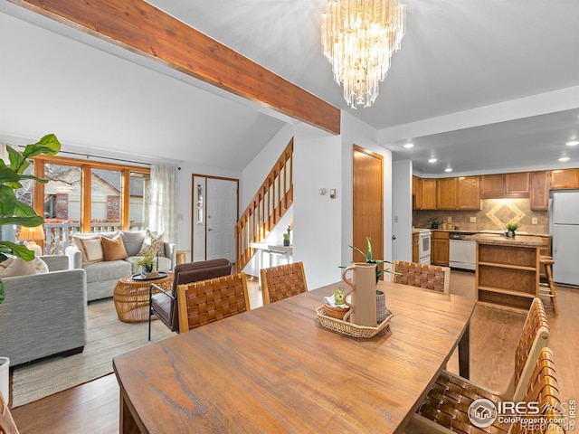 dining room with beam ceiling, light hardwood / wood-style floors, and a chandelier