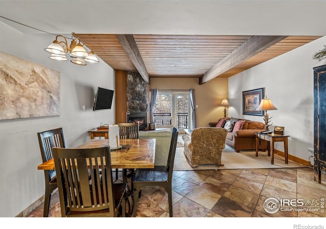 dining area with a fireplace, beamed ceiling, a chandelier, and wood ceiling