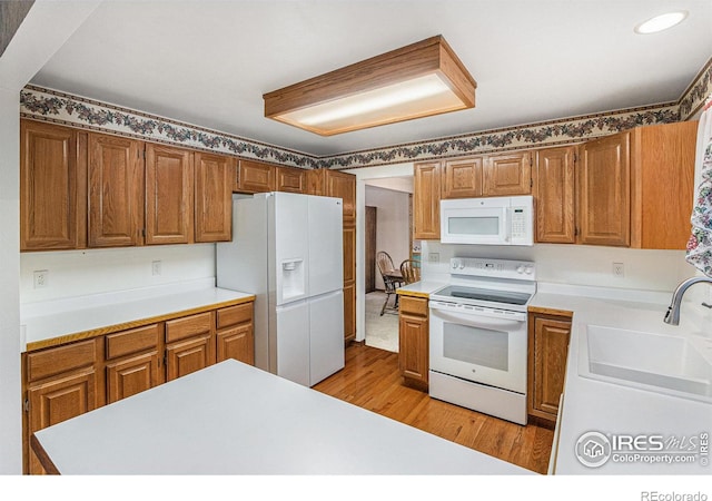 kitchen with light hardwood / wood-style flooring, sink, and white appliances