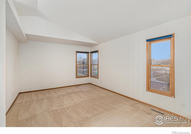 empty room with light colored carpet and vaulted ceiling