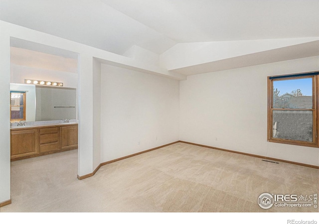 unfurnished room featuring lofted ceiling, sink, and light colored carpet