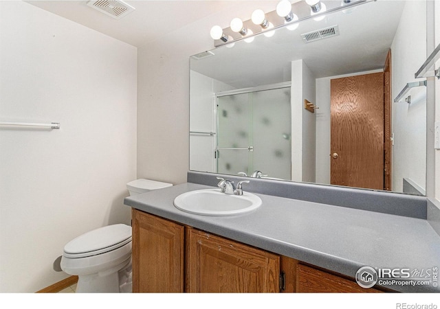 bathroom featuring toilet, vanity, and a shower with shower door