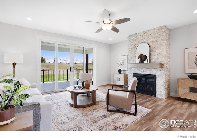 living room featuring a fireplace, wood-type flooring, and ceiling fan