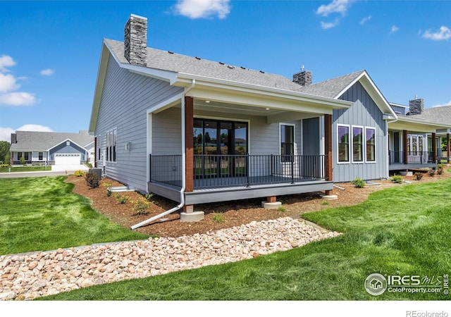 rear view of property featuring a garage and a lawn